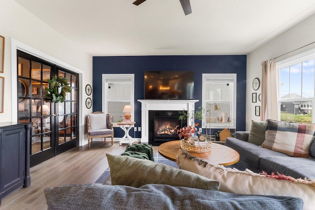 living room featuring a premium fireplace, light hardwood / wood-style flooring, and ceiling fan