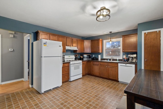 kitchen with pendant lighting, white appliances, and sink