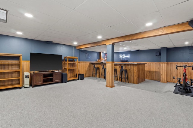 basement with carpet, bar, and wood walls