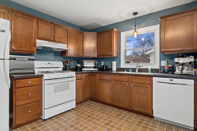 kitchen featuring decorative light fixtures, white appliances, and sink