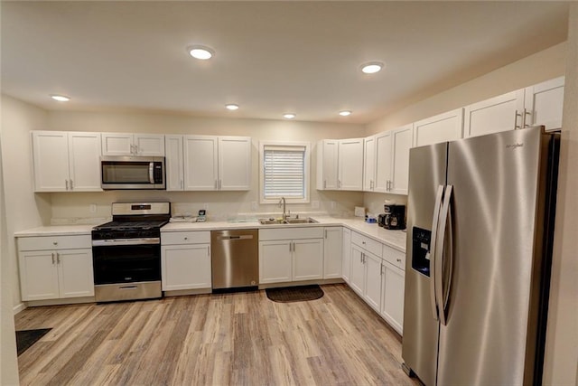 kitchen featuring white cabinets, appliances with stainless steel finishes, light wood-type flooring, and sink