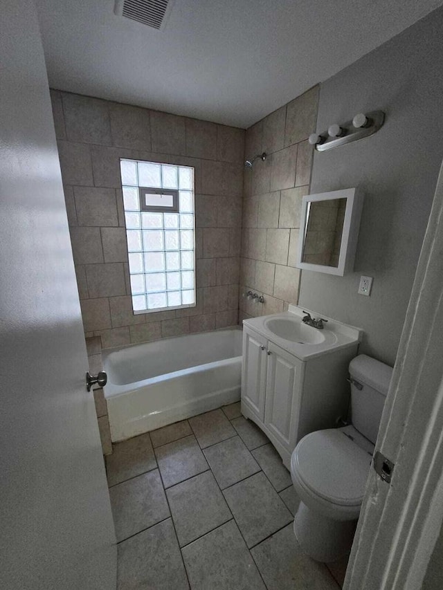 full bathroom featuring tile patterned floors, vanity, toilet, and tiled shower / bath combo