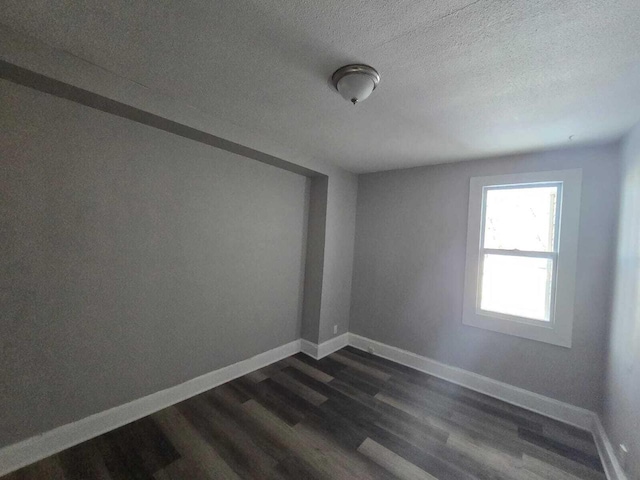 empty room with a textured ceiling and dark wood-type flooring