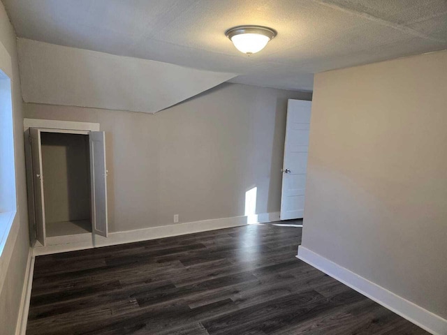 unfurnished room with a textured ceiling and dark wood-type flooring