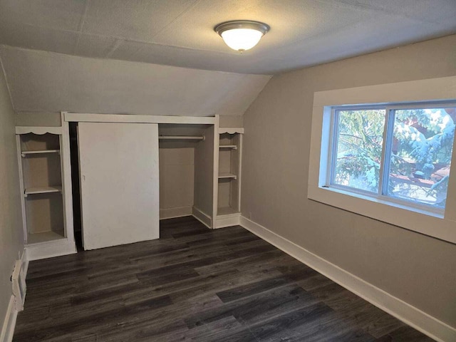 unfurnished bedroom with vaulted ceiling, dark wood-type flooring, and a closet