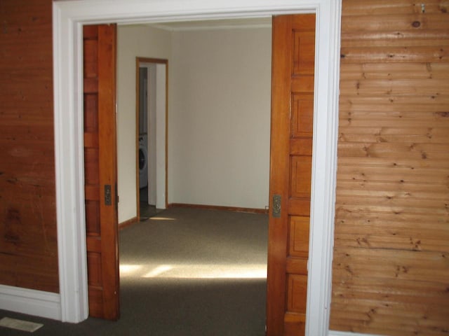 hallway featuring carpet and wood walls