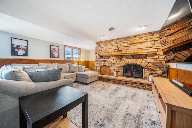 living room with a fireplace, a textured ceiling, and wood walls