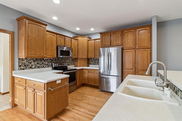 kitchen with decorative backsplash, stainless steel appliances, light hardwood / wood-style flooring, and sink