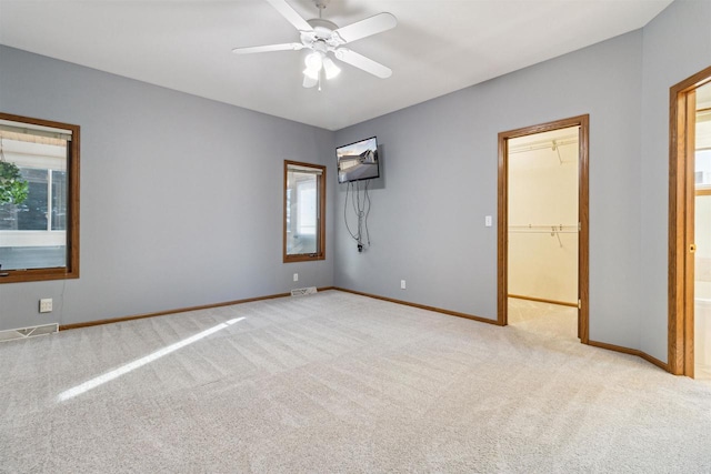 unfurnished bedroom featuring ceiling fan, a closet, light colored carpet, and a spacious closet