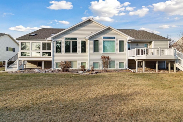 back of property with a yard, a deck, and a sunroom