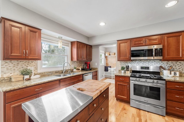 kitchen featuring a kitchen island, appliances with stainless steel finishes, sink, stainless steel counters, and light hardwood / wood-style flooring