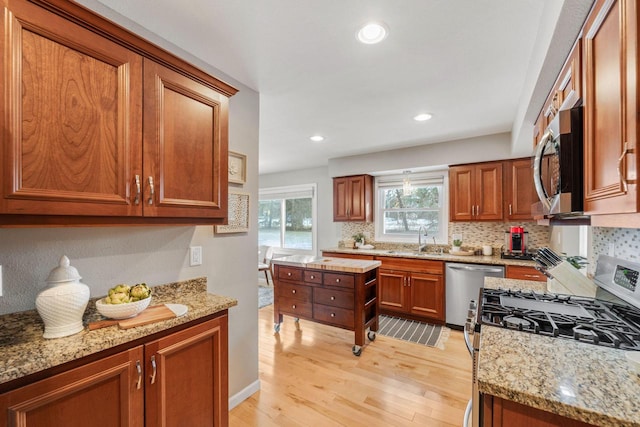 kitchen featuring light stone counters, stainless steel appliances, light hardwood / wood-style floors, and sink