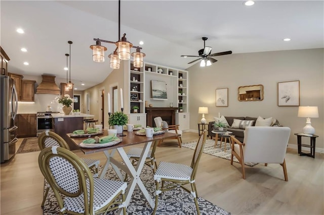 dining space featuring ceiling fan, light wood-type flooring, and vaulted ceiling