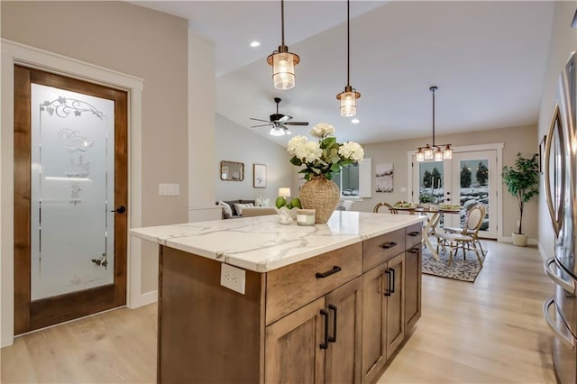 kitchen with light wood finished floors, lofted ceiling, light stone counters, and freestanding refrigerator