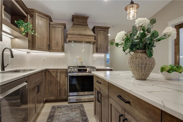 kitchen with light stone countertops, custom exhaust hood, open shelves, a sink, and stainless steel appliances