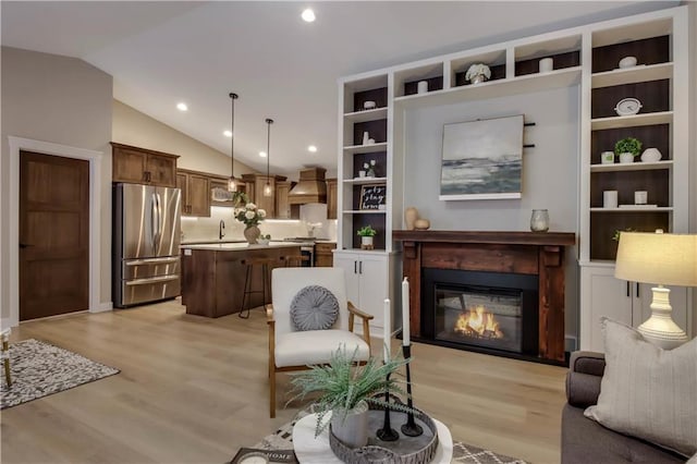 sitting room featuring recessed lighting, light wood finished floors, a glass covered fireplace, and vaulted ceiling