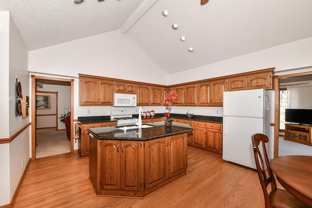 kitchen with a textured ceiling, a center island, light hardwood / wood-style floors, and white appliances