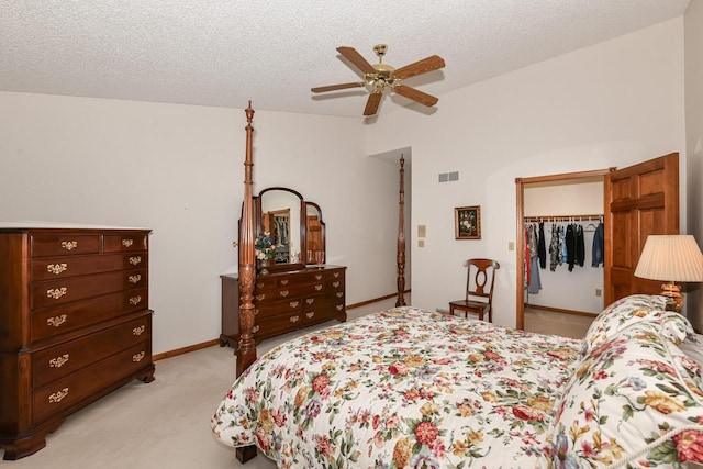 bedroom featuring ceiling fan, a spacious closet, a textured ceiling, light colored carpet, and a closet