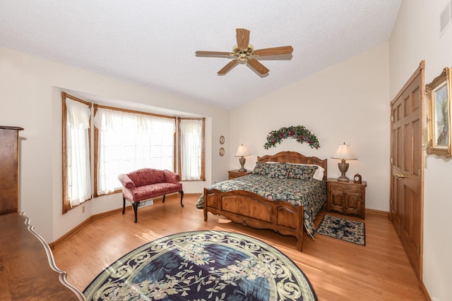 bedroom with a textured ceiling, light hardwood / wood-style floors, vaulted ceiling, and ceiling fan