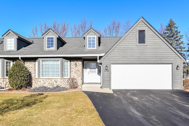 cape cod house featuring a front lawn and a garage