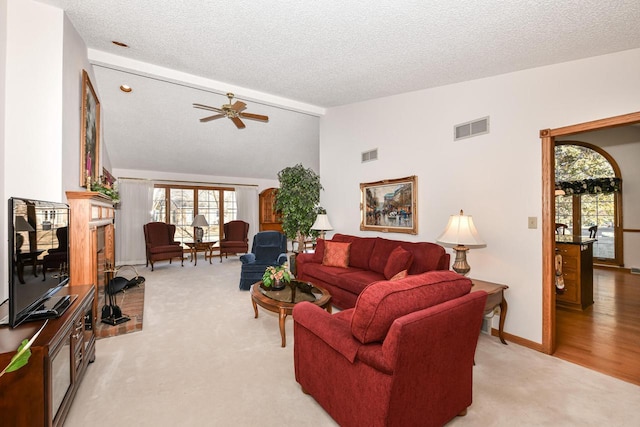 carpeted living room with a fireplace, a textured ceiling, vaulted ceiling, and ceiling fan