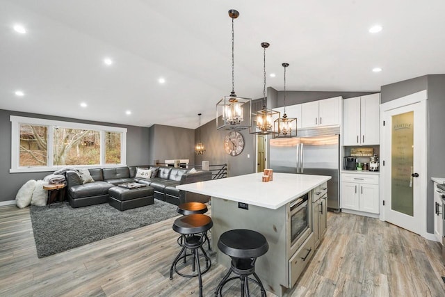 kitchen with built in appliances, white cabinetry, a kitchen island, and lofted ceiling