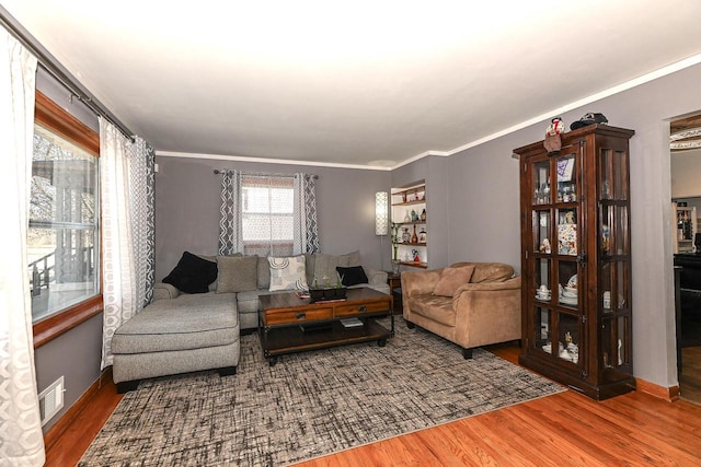 living room featuring wood-type flooring and crown molding