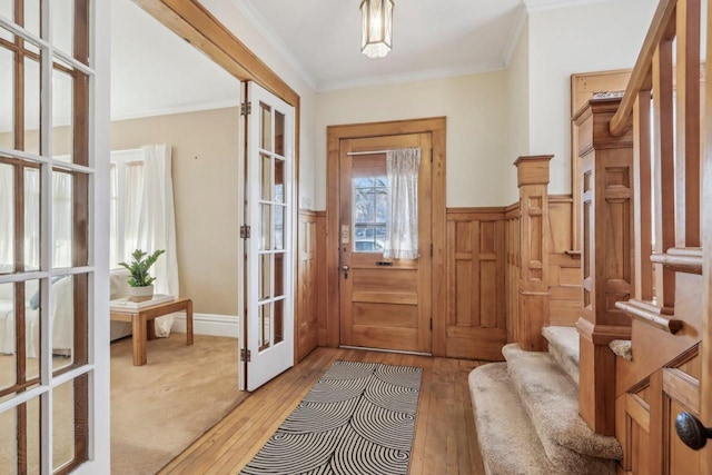 doorway to outside with crown molding, light hardwood / wood-style flooring, and french doors