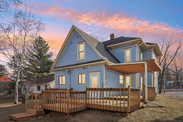 back house at dusk with a wooden deck