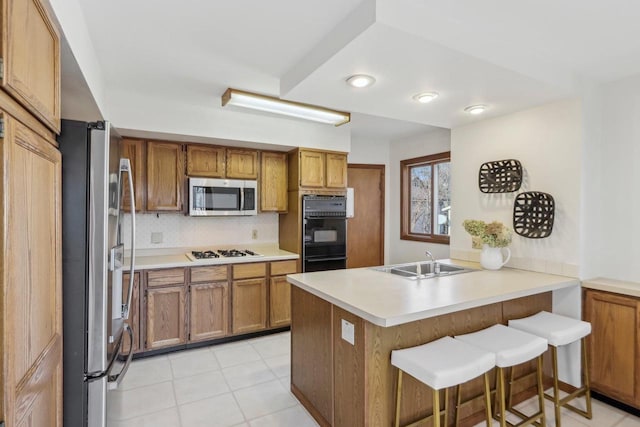 kitchen featuring kitchen peninsula, appliances with stainless steel finishes, a kitchen bar, tasteful backsplash, and light tile patterned floors