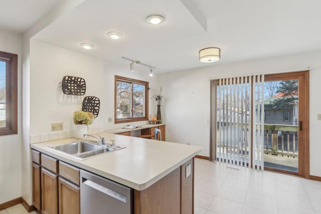 kitchen with kitchen peninsula, a wealth of natural light, dishwasher, and sink