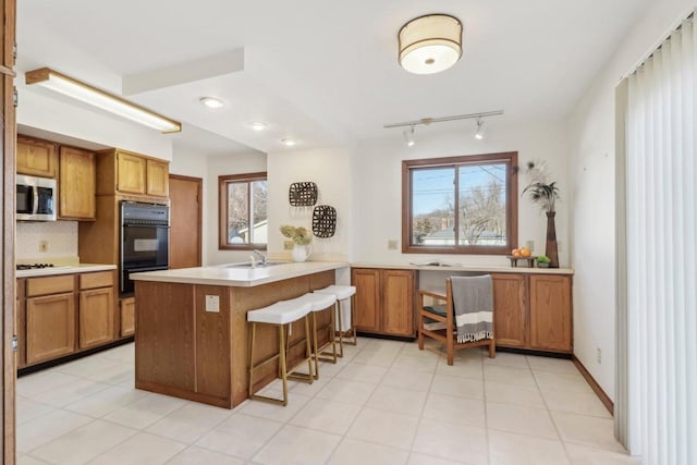 kitchen featuring white gas cooktop, a kitchen bar, kitchen peninsula, and a wealth of natural light