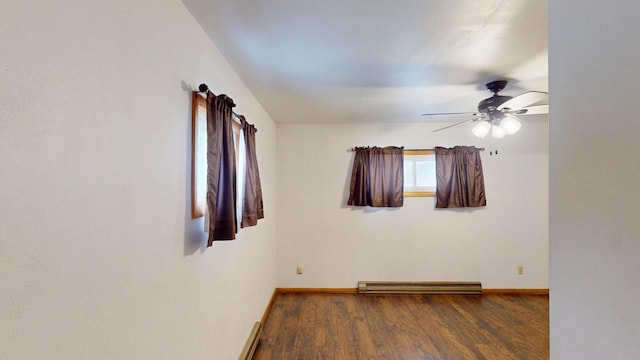 spare room featuring ceiling fan, dark wood-type flooring, and a baseboard heating unit