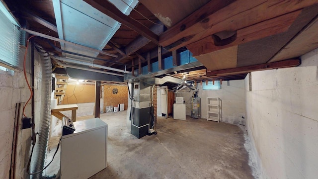 basement with heating unit, refrigerator, gas water heater, and washer / dryer