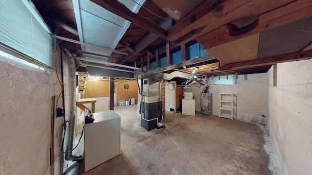 basement with heating unit, water heater, refrigerator, and washer / dryer