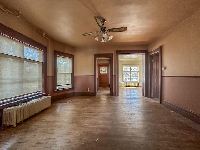 spare room featuring ceiling fan, radiator heating unit, and dark wood-type flooring