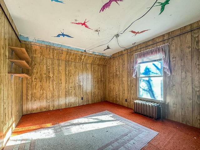 carpeted empty room with radiator and wooden walls