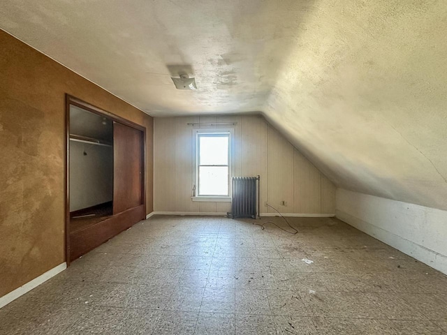 bonus room featuring a textured ceiling, radiator, and lofted ceiling