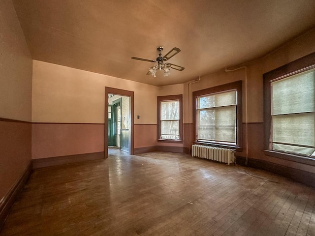 unfurnished room featuring radiator, ceiling fan, and hardwood / wood-style floors