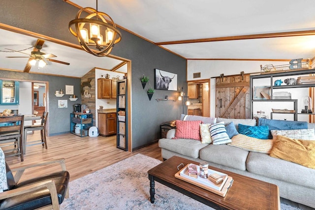 living room with ceiling fan with notable chandelier, crown molding, a barn door, light hardwood / wood-style flooring, and lofted ceiling