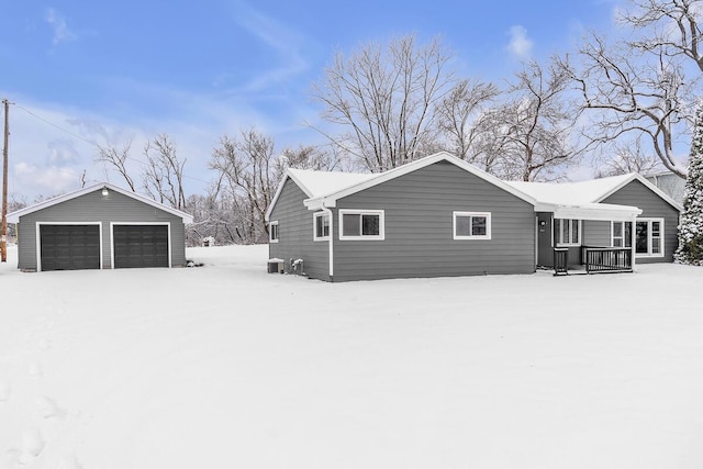 view of snow covered exterior featuring covered porch, a garage, an outbuilding, and central AC