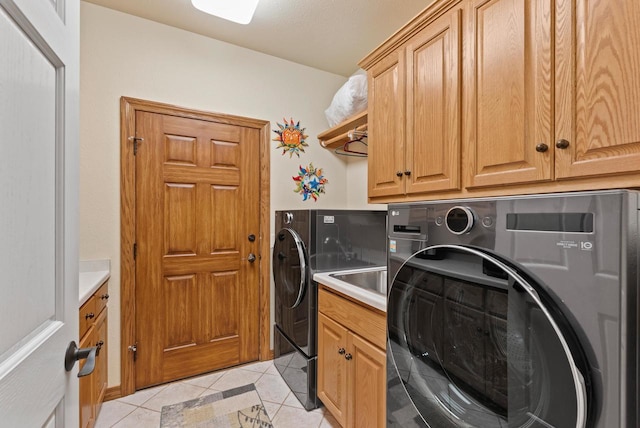 laundry room featuring separate washer and dryer, light tile patterned floors, and cabinets