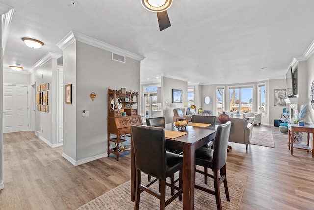 dining area with ceiling fan, light wood-type flooring, and crown molding