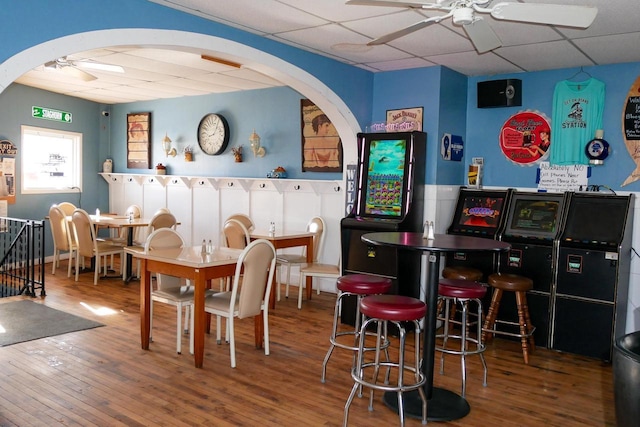 interior space with a paneled ceiling, hardwood / wood-style floors, and ceiling fan