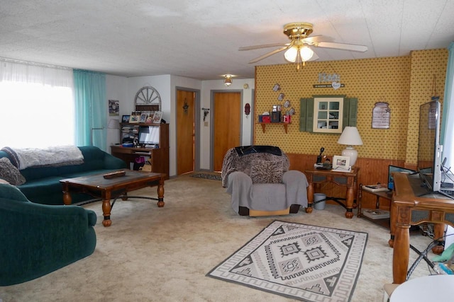 carpeted living room featuring a textured ceiling, ceiling fan, and wooden walls