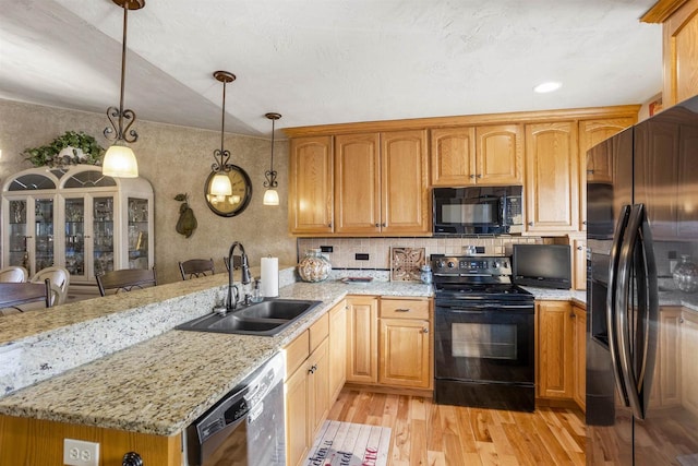 kitchen with sink, a kitchen breakfast bar, light hardwood / wood-style flooring, decorative light fixtures, and black appliances