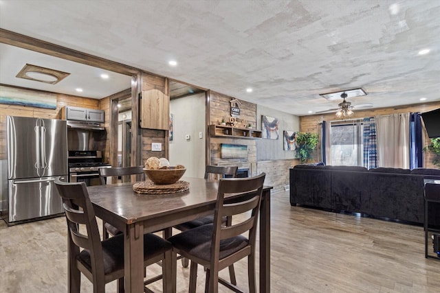 dining room with a fireplace, ceiling fan, and light hardwood / wood-style flooring