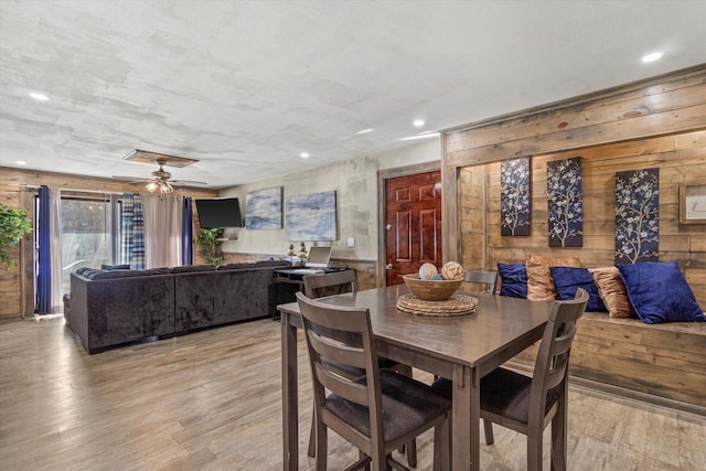 dining space with light wood-type flooring and wood walls