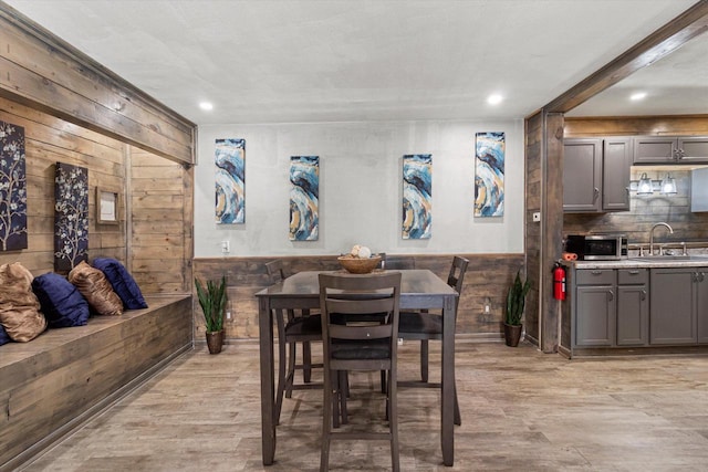 dining area with sink, wood walls, and light wood-type flooring