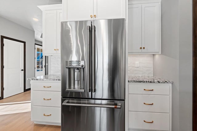 kitchen featuring white cabinetry, light stone counters, light hardwood / wood-style floors, decorative backsplash, and high end fridge